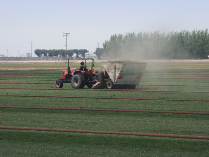 tractor using fuel to vacuum grass clippings on a sod farm