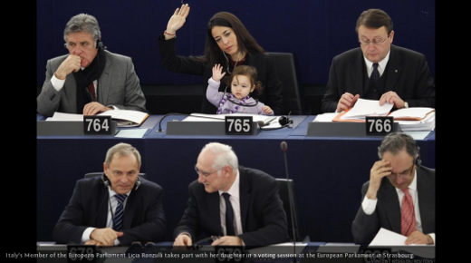 Licia Ronzulli, Italian Member of the European Parliament, with her daughter on her lap, raising her hand to vote on an issue during a session of Parliament